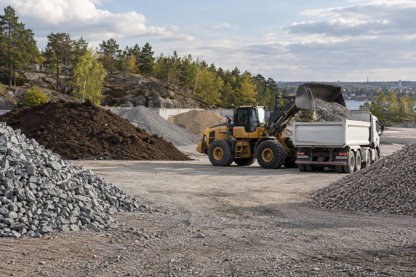 Hjullastare som lastar bergkross på en lastbil vid ett massupplag